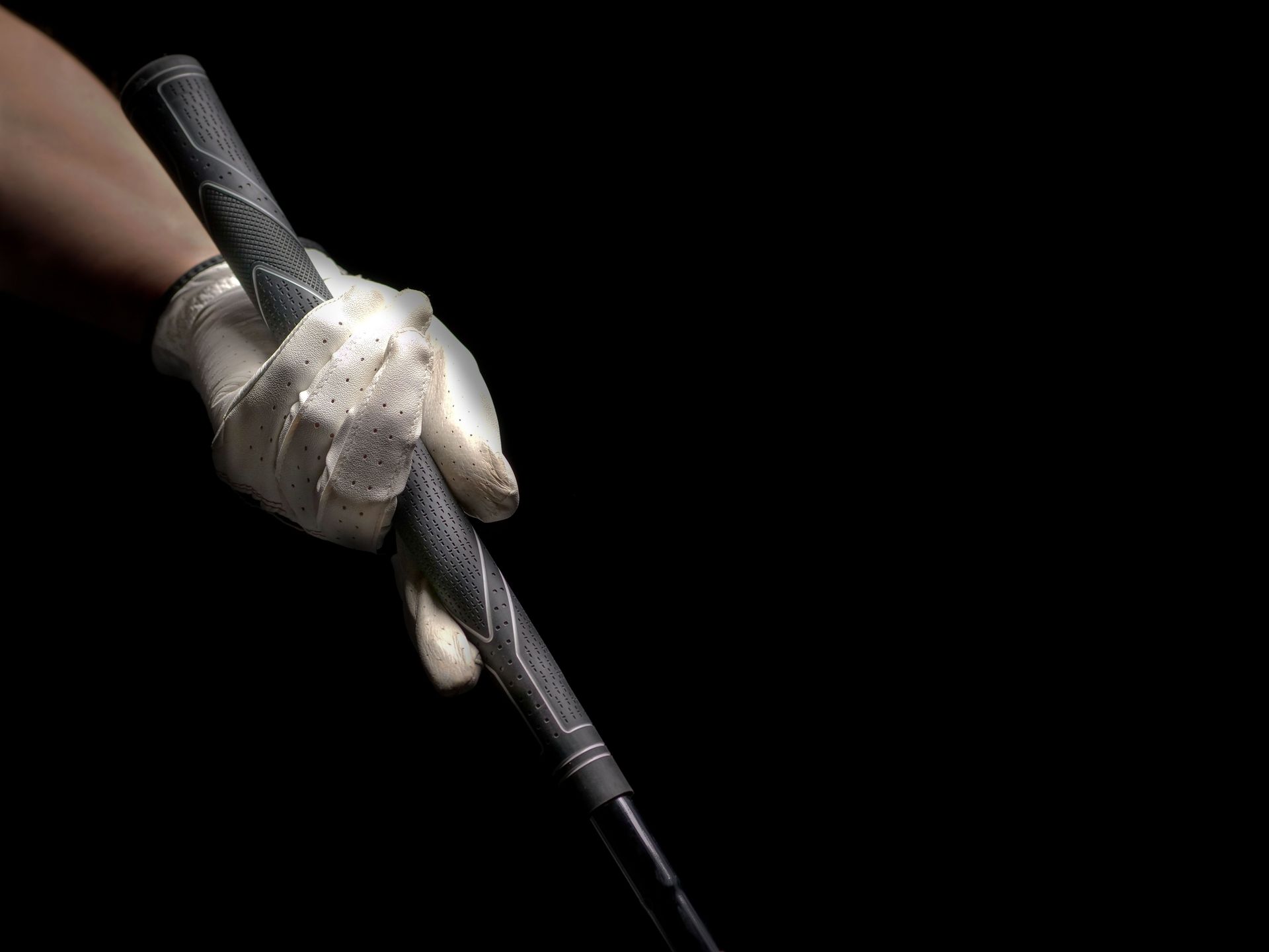 Golf glove hand gripping a club against a black backdrop, showcasing sports focus and precision.
